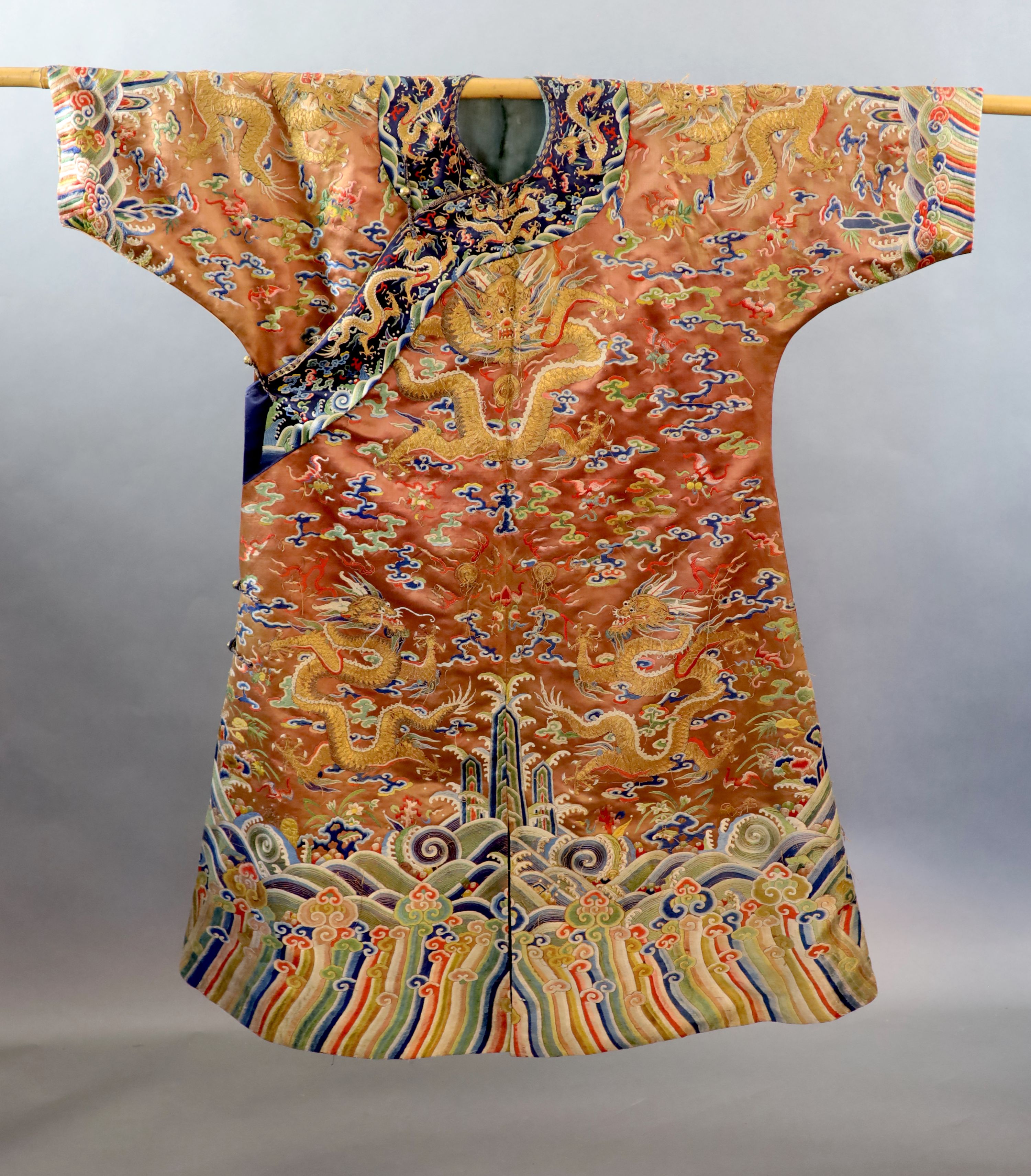 A Chinese apricot embroidered silk ‘dragon’ formal court robe, jifu, late Qing Dynasty, 131cm long, some alterations